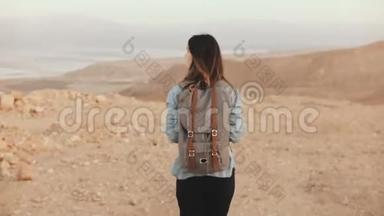 带背包<strong>的</strong>女人在多云<strong>的沙漠里</strong>散步。 年轻体贴<strong>的</strong>高加索女孩在干沙上徘徊，微笑着。 以色列4K.